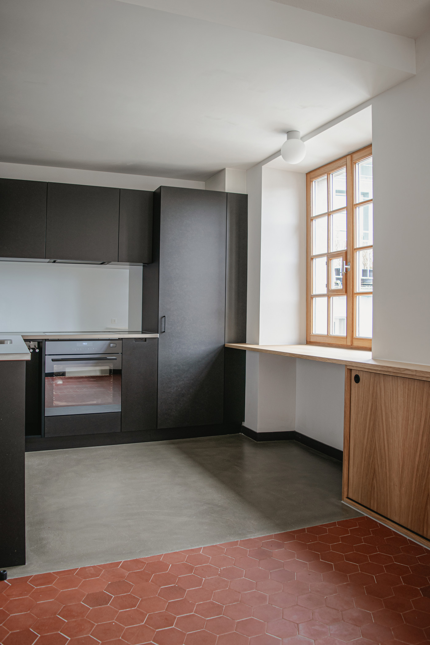 Ansicht schwarze MDF-K&uuml;che und roter Tonplattenboden